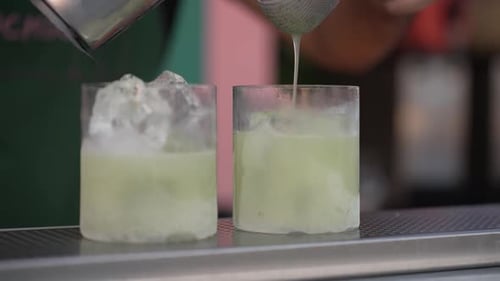 Bartender Straining Cocktail into Ice Filled Glass