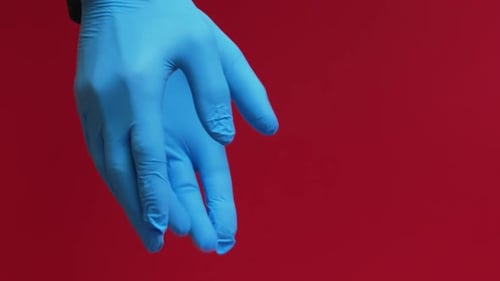Gloved Hand Places Wrapped Gift on Red Surface