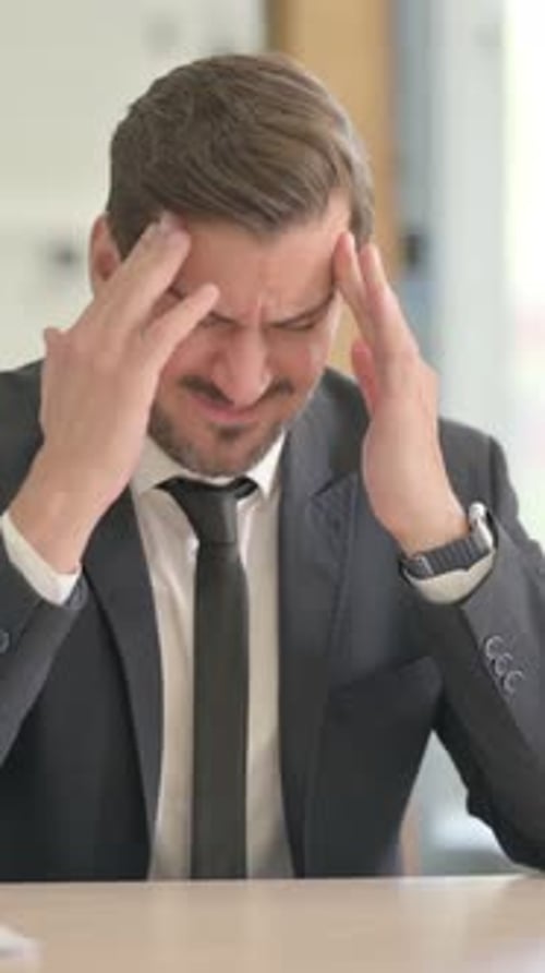Stressed Businessman with Headache Rubbing Temples at Desk