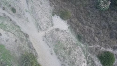Aerial drone shot tracking forward at medium height looking down over a grassy beach park.