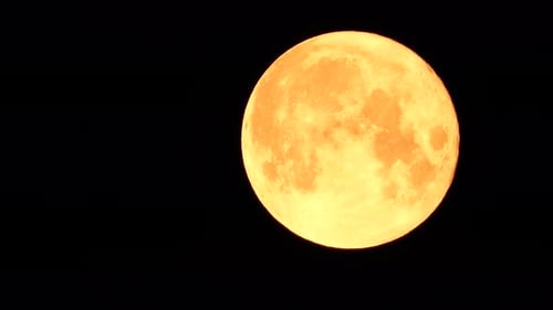 Une énorme pleine lune dorée et rougeoyante vue de la Terre à travers l'atmosphère sur fond de ciel étoilé