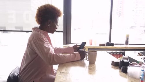 Businesswoman With Smart Phone Taking Notes At Cafe Counter