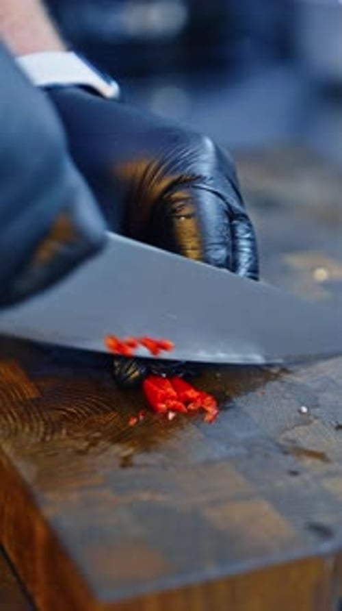 Hands in Gloves Dicing Red Pepper on Wood