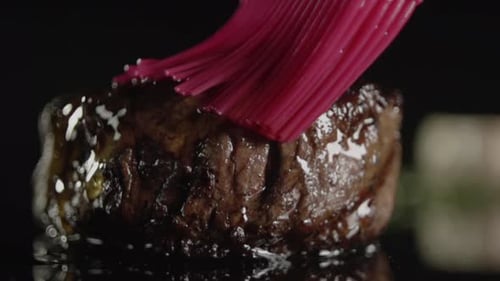 A cooked steak is basted with butter