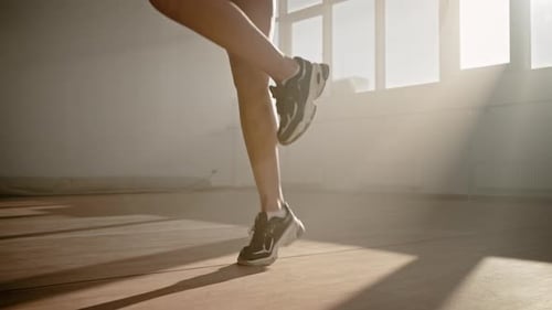 Nahaufnahme der Beine einer Sportlerin, die mit Springseil springt, in einem verrauchten Fitness-Interieur