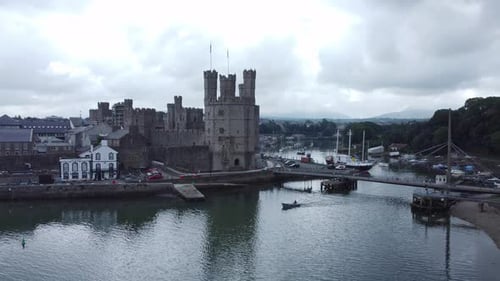 Ancient Caernarfon castle Welsh harbour town aerial view medieval waterfront landmark descending to