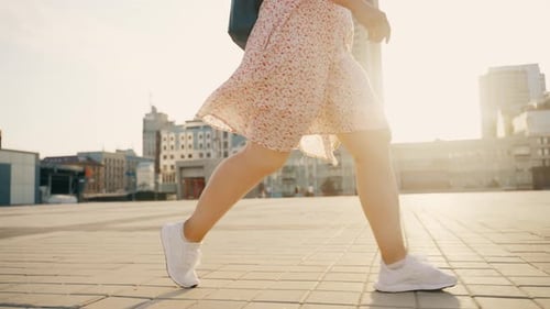 Close Up of Female Legs in Stylish White Sneakers Walking Along the City Street