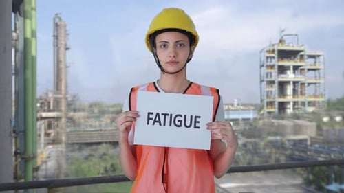 Sad Indian female construction worker holding FATIGUE banner
