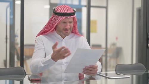 Man Wearing Headscarf Expresses Frustration at Desk