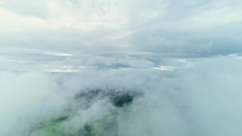 Floating slowly through clouds with a glimpse of green land underneath.