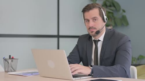 Businessman with Headset Looking toward Camera in Call Center