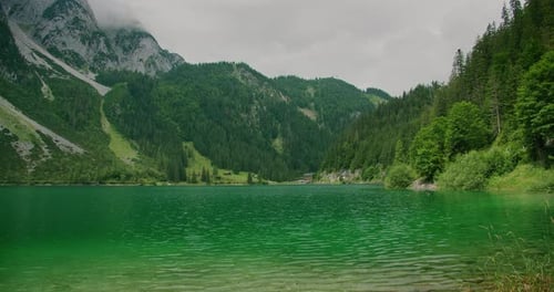 Lago alpino verde enmarcado por escarpadas montañas boscosas y un acogedor pueblo junto al lago