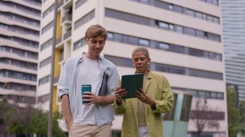 Young Man and Woman Walk and Use Tablet