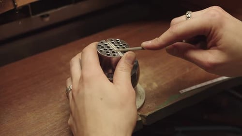 A Person is Working on a Piece of Jewelry Using a Tool to Shape It