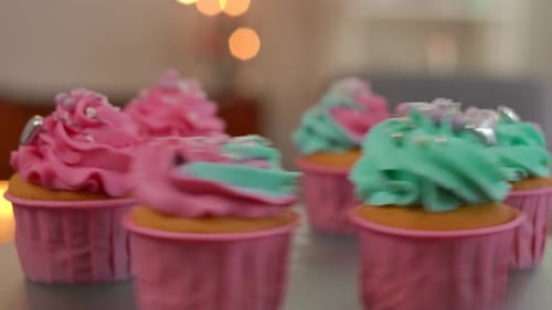 Side View Closeup Glass Tray Spinning with Tasty Muffins Decorated with Royal Icing and Edible