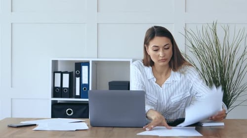 Professional Woman Working at Her Desk Focused on Tasks in a Modern Office