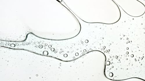 Swirling Clear Liquid with Bubbles on Bright Surface
