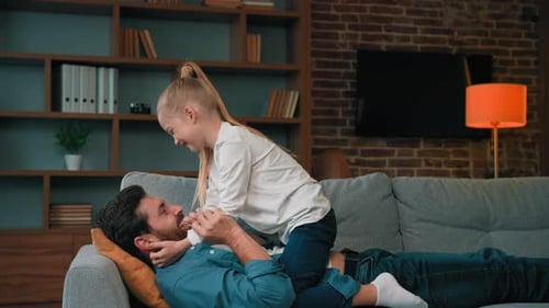 Father and Daughter Laughing Together on Sofa