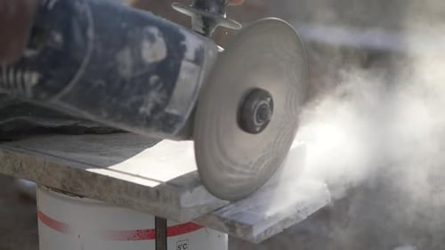 A Person is Using a Grinder to Cut an Auto Part Made of Steel