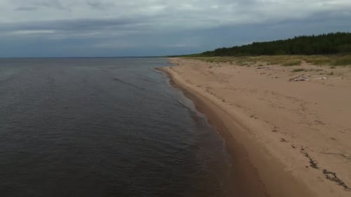 Coastal Serenity Aerial Shot Captures the Natural Beauty of a Sandy Beach and Water Under a Cloudy