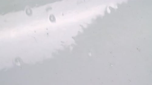 Água com bolhas fluindo para baixo em uma parede lisa e brilhante. - de perto