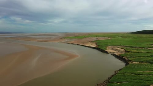 Aerial shot descending over a coastal bay, on a bright sunny day, natural pattens at low tide.