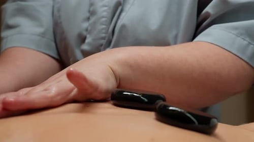 Massothérapie relaxante aux pierres chaudes pour le dos avec des pierres chauffantes lisses et un toucher doux