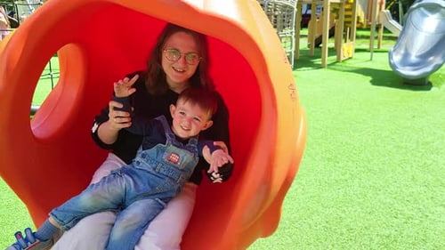 The mother and child are sitting together on the swings, enjoying the joy of swinging in the playgro