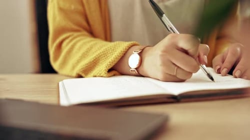 Woman Writes in Notebook at Desk in Office