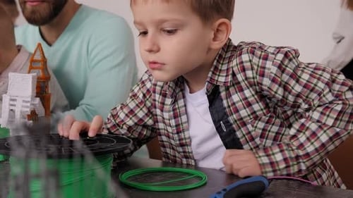 A Little Boy Holding Colored Plastic for a 3D Pen at a Robotics School