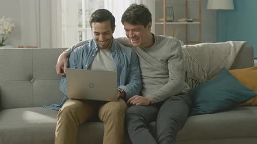 Happy Men Using Laptop Together on Sofa