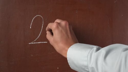 Textured Brown Chalkboard Background Male Hand Writing Addition Equations on the Board with a Piece