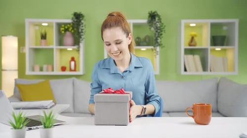 Woman Tying Ribbon on Gift Box at Home
