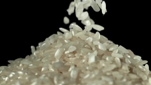 Rice Grains Falling Against Black Background