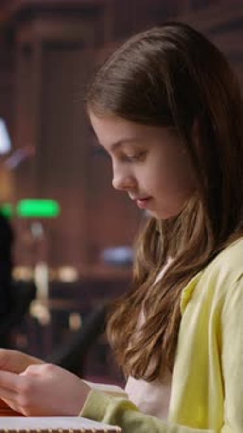 Vertical Video Focused Schoolgirl Reading a Book in the Library for Mandatory Literature