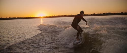 A Surfer Riding a Wave at Sunset Capturing the Thrill and Freedom of Water Sports in a Serene