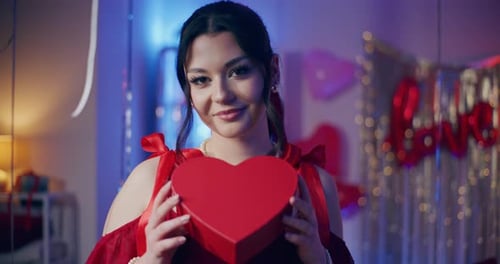 Smiling Woman Holding Heart Gift Box Indoors