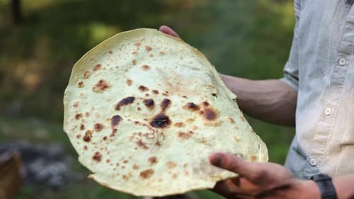 Adult Making Flatbread Outdoors Over a Campfire
