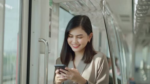 A young beautiful businesswoman is using smart phone on Metro train
