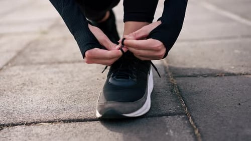 Close-up of female hands tying the laces on special running shoes during morning workout