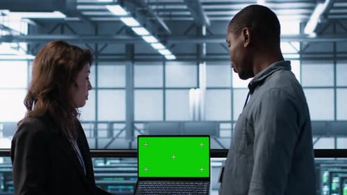 Colleagues Review Green Screen Laptop in Modern Workplace