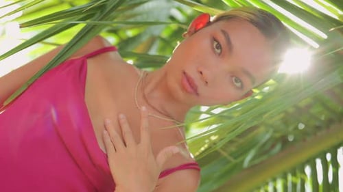 Vertical Video Young Charming Asian Girl Posing with Hands in the Palms Leaf Wearing Pink Long Silk
