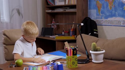 Focused Child Reading Book at Table Indoors
