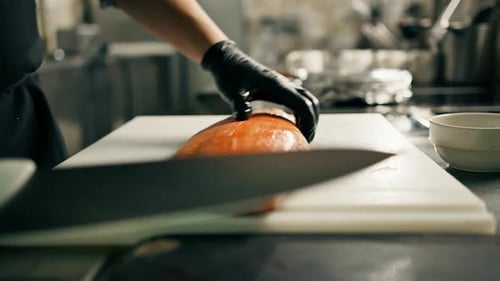 Professional kitchen in the hotel restaurant The chef cuts a large fresh salmon carcass with a knife