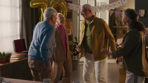 Companhia de amigos idosos alegres dançando energicamente durante a festa de aniversário