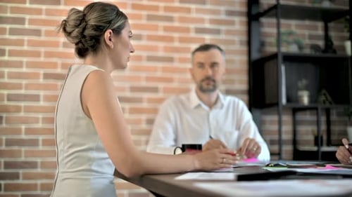 Three people are working and talking in the office. Papers with graphs and information