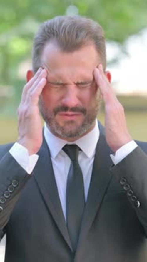 Man in Suit Experiences Headache Outdoors