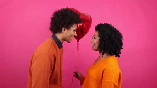 Smiling Couple Shares Romantic Kiss with Heart Balloon