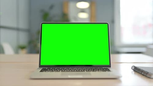 Laptop with Green Screen on Desk in Office