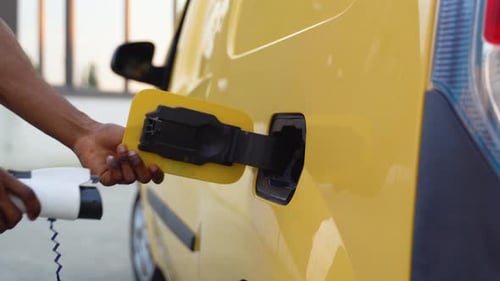 African American Man Charging Cargo Electric Car Near Warehouse Green Energy Eco Friendly Fuel